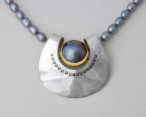 Silver form with a Marbé Pearl set in gold on grey fresh water Pearls